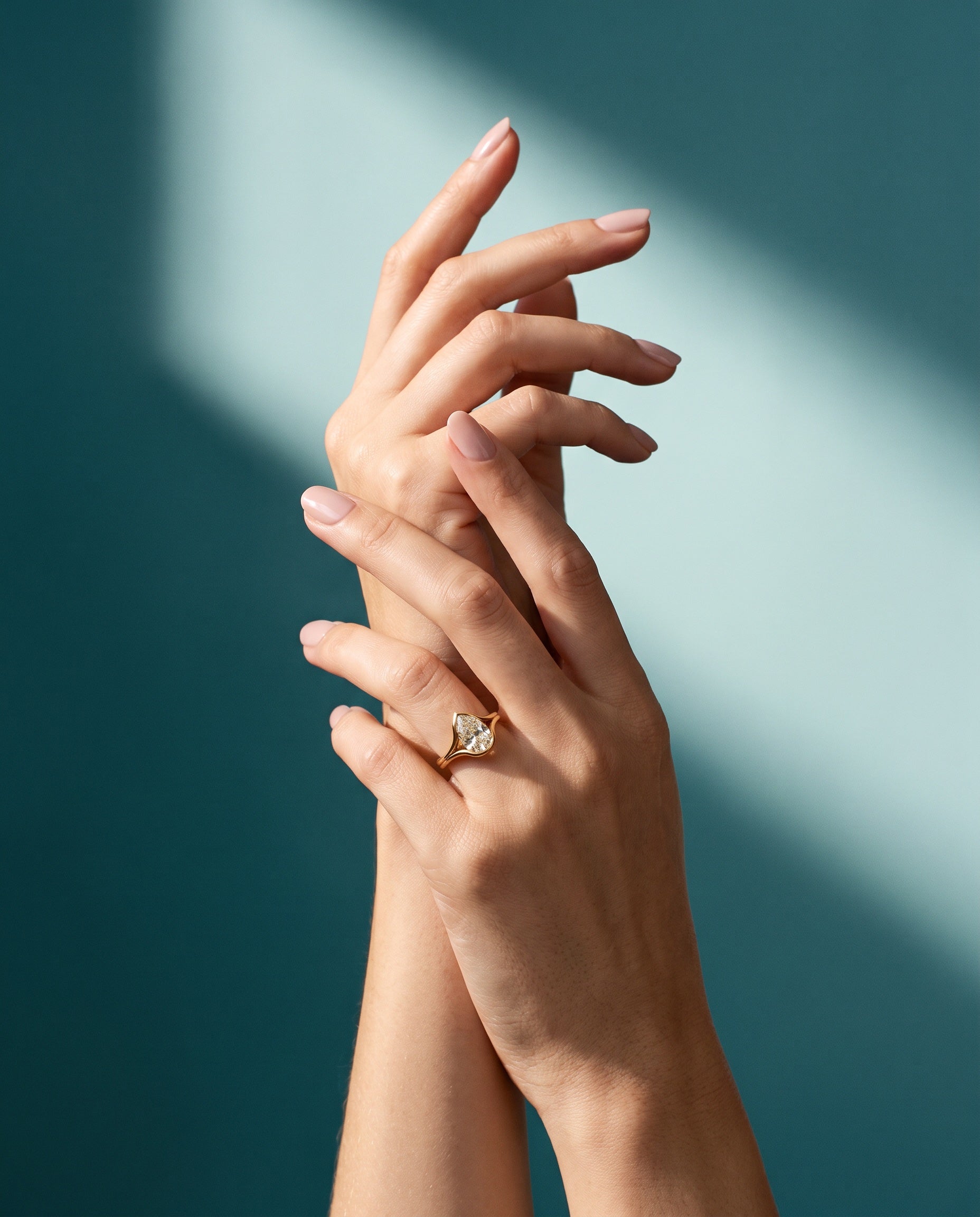 Pear-shaped ring worn against a deep teal background